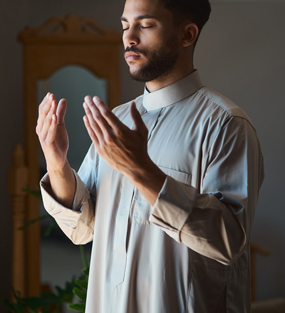 Prayer enlarges the heart. Shot of a young muslim man praying in the lounge at home